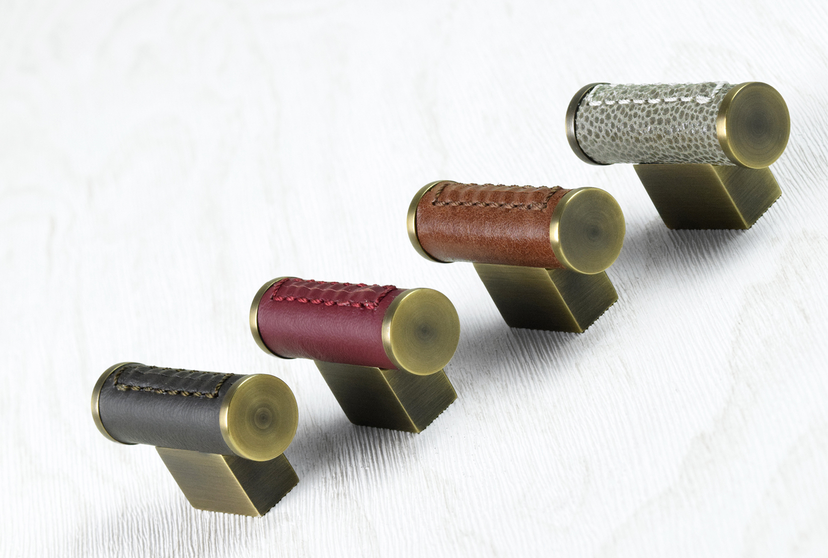 Image of four scroll cabinet t bars, finished in a selection of custom coloured leathers. The base and end cap are finished in fine antique.