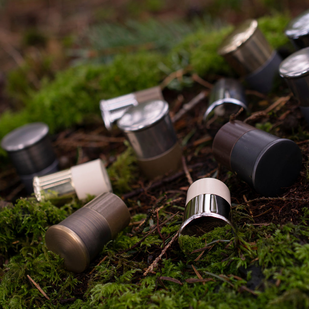 Turnstyle Designs cartridge cabinet knobs, designed to look like a shot gun cartridge, lay on a bed of green moss in a moody wood. The The cabinet knobs have been laid out to look like shot gun cartridges that have been expelled straight form the gun.