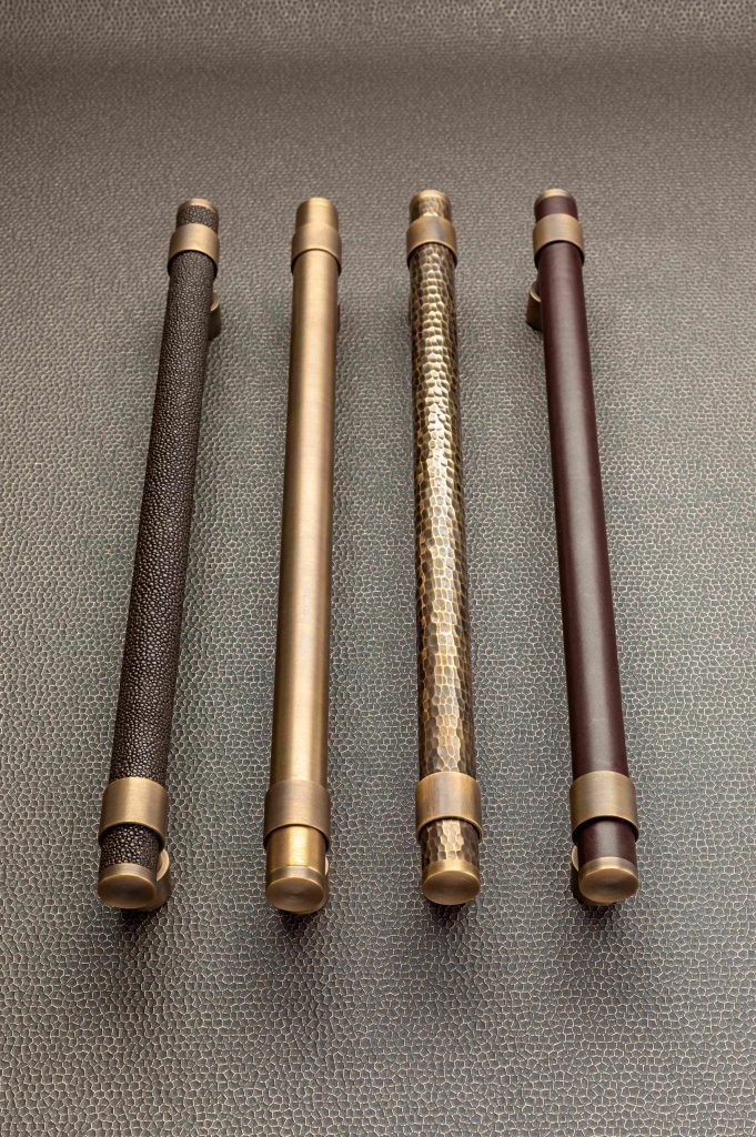 4 large stepped door pulls by Turnstyle Designs. Showing all four of their signature materials, Amalfine, Solid Brass, Hammered brass and Italian leather.