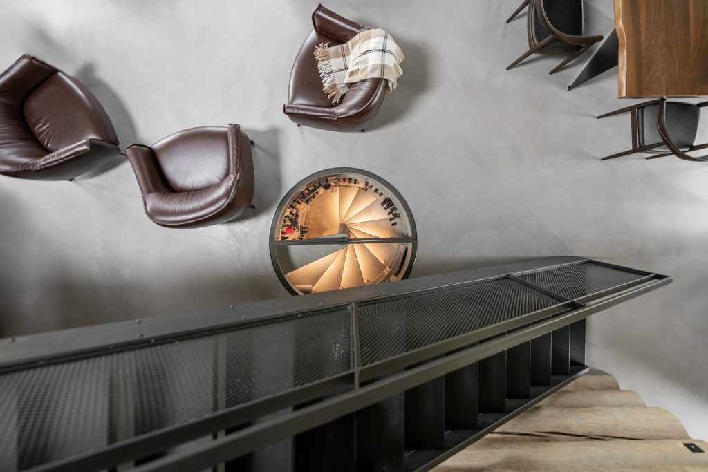 House of the hunter project by FORM studio interior design. Central to this image of a brids eye view from the stairs show the unique and striking wine circular wine cellar in the concrete floor.