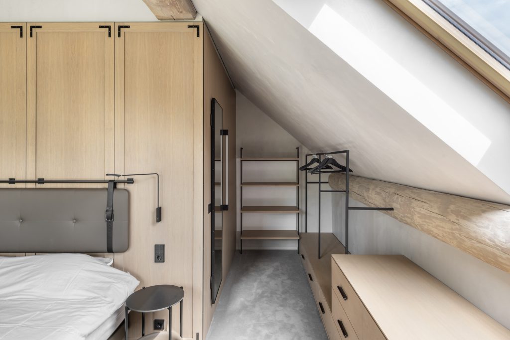 A bedroom with sky light floods light into a wooden theme, scandi style interior. Mixed with leather, wood and brass finishes.