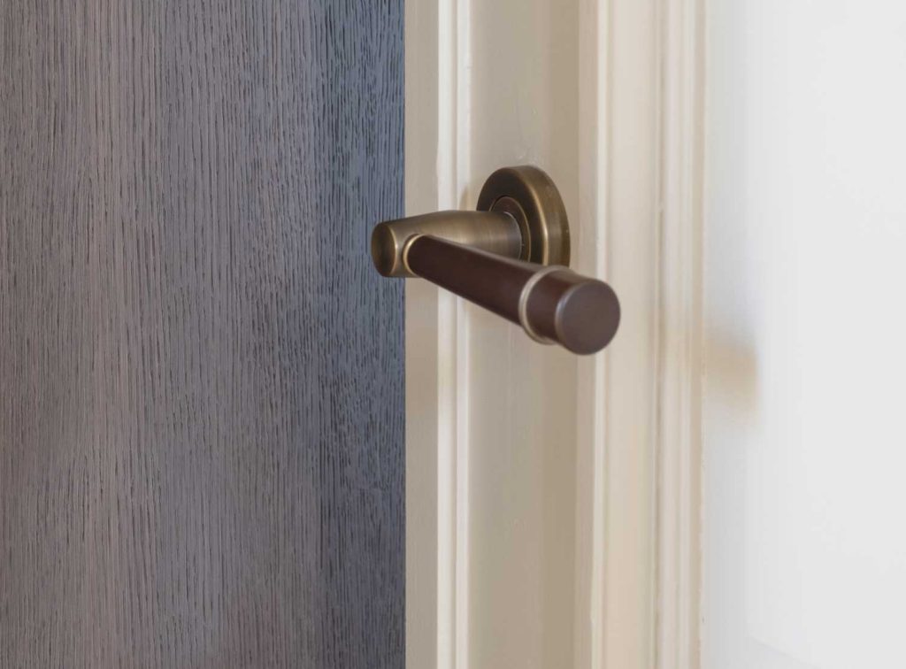 The Flute design door lever by Turnstyle Designs is shown here on a newly restored door in an Antwerp apartment project. The tapered gip design made from Amalfine has a decorative brass ring at the far end matching the brass finish of the rose and lever shaft.