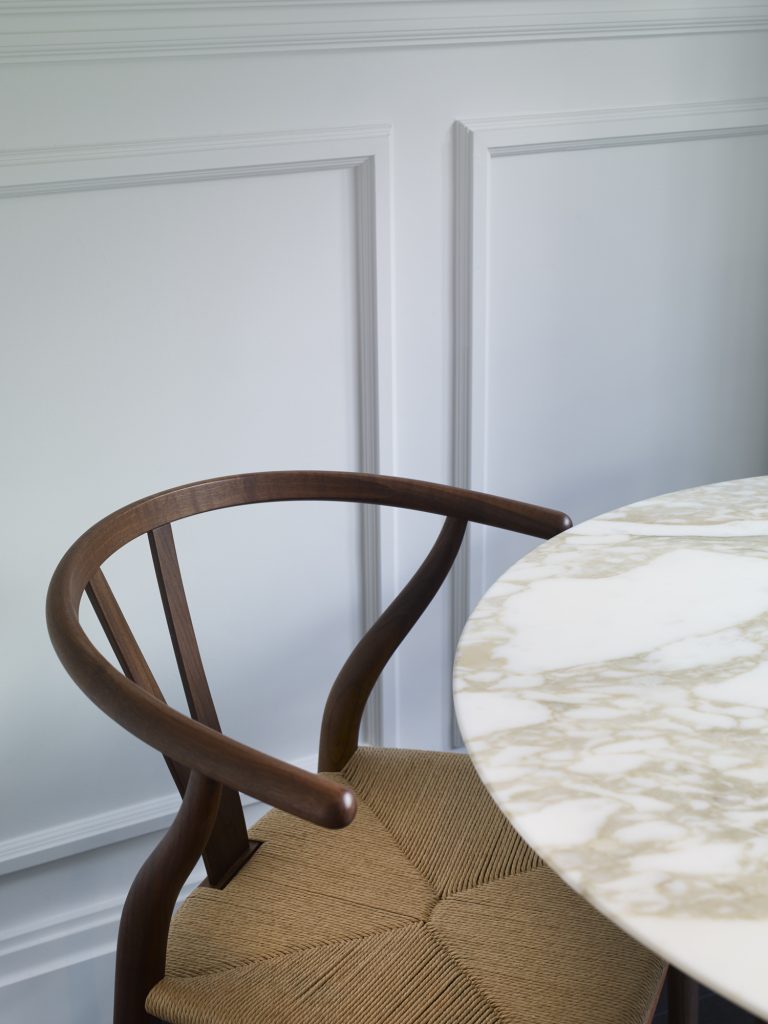 Lucia Vega and Sophie Standbury create a luxurious interior in London based apartment. Unique furniture and bespoke elements were chosen. Shown here is a wooden curved dining chair next to a circular marble table.