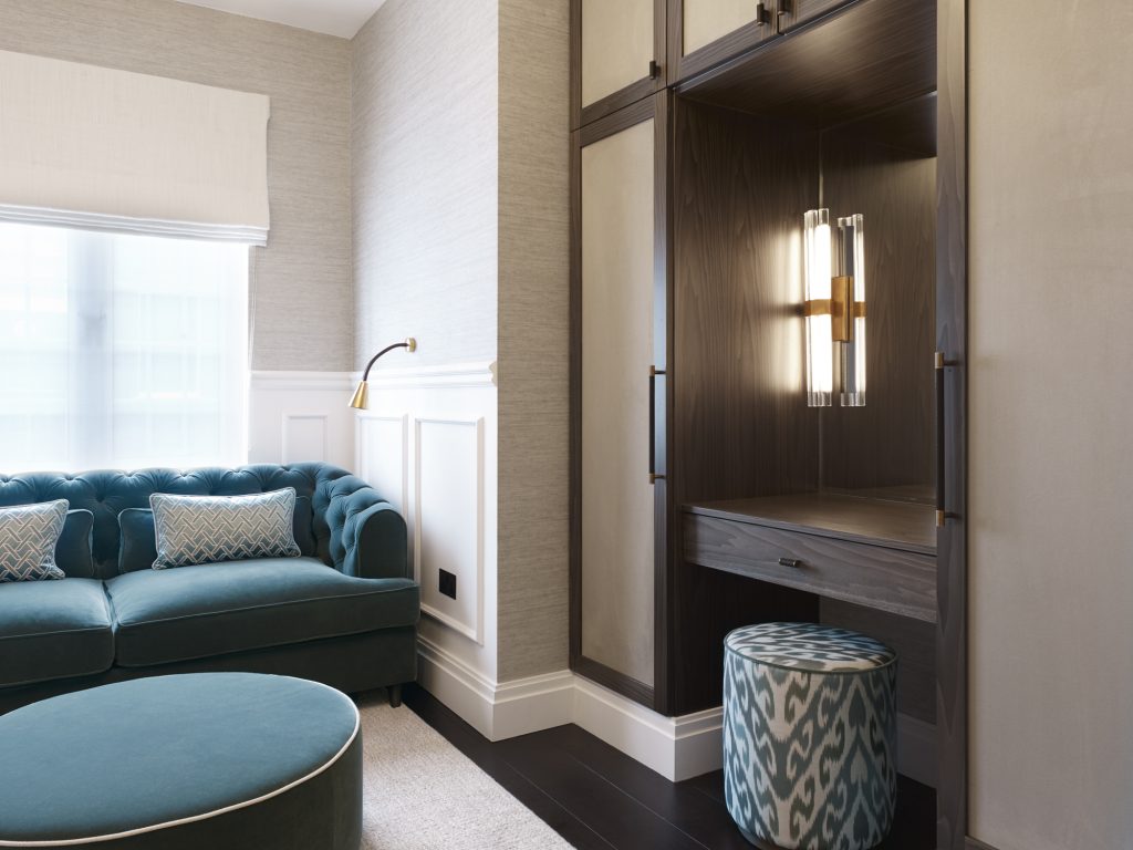 Luxury high-end interior with chesterfield style turquoise sofa, dark wood and textured panelled bespoke joinery with handmade, bespoke cabinet handles.